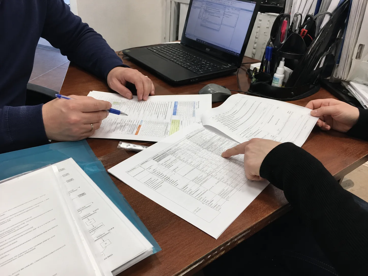 Двое сотрудников сверяют документы водителя по таблице за рабочим столом
